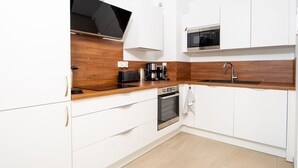 A modern kitchen with white cabinets, a wooden countertop, a built-in oven, a microwave, and a black range hood. - Blue Pearl 206 by Avecoeur (Nice)