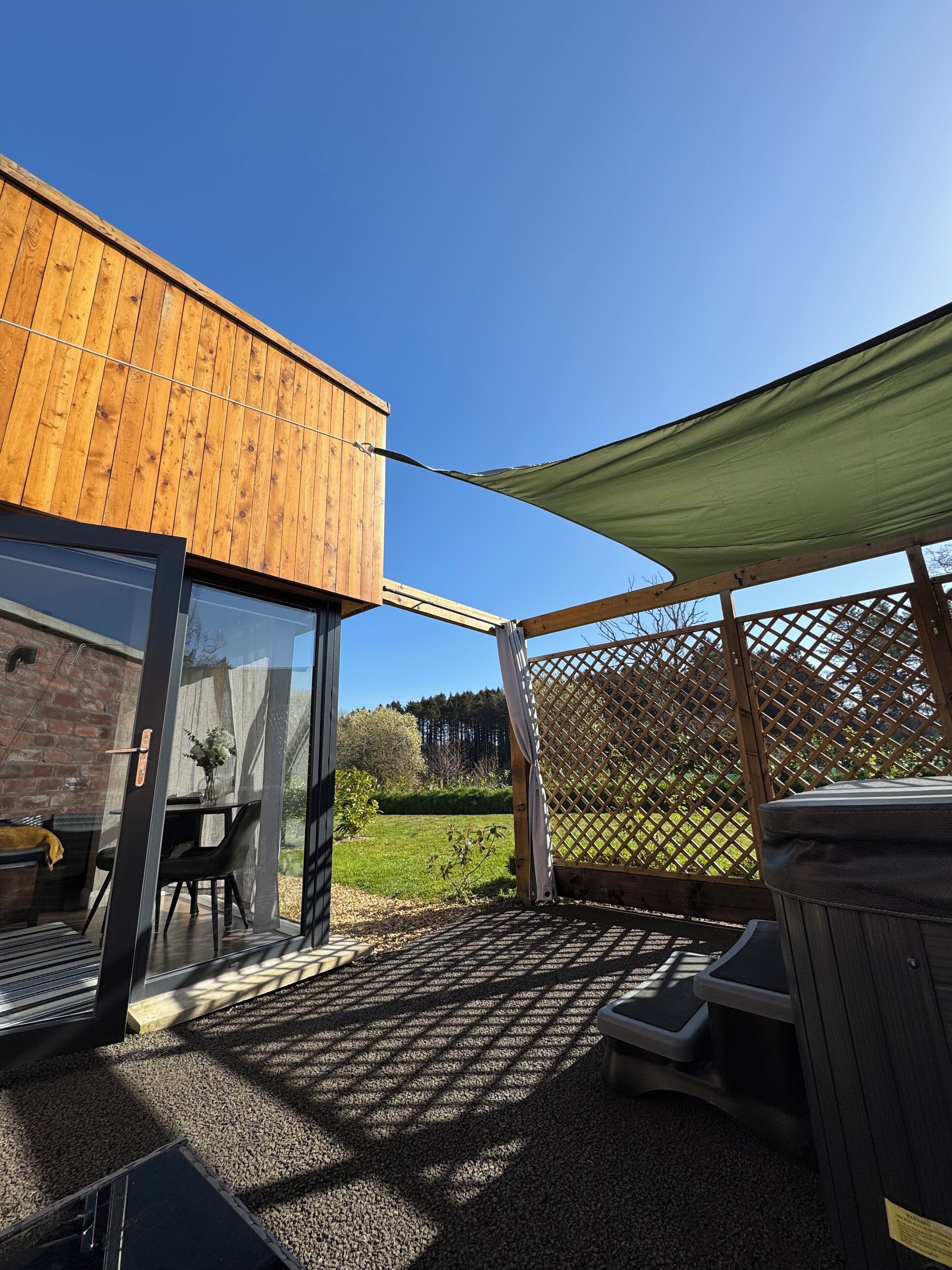 A wooden deck with a glass door leading to a patio area.