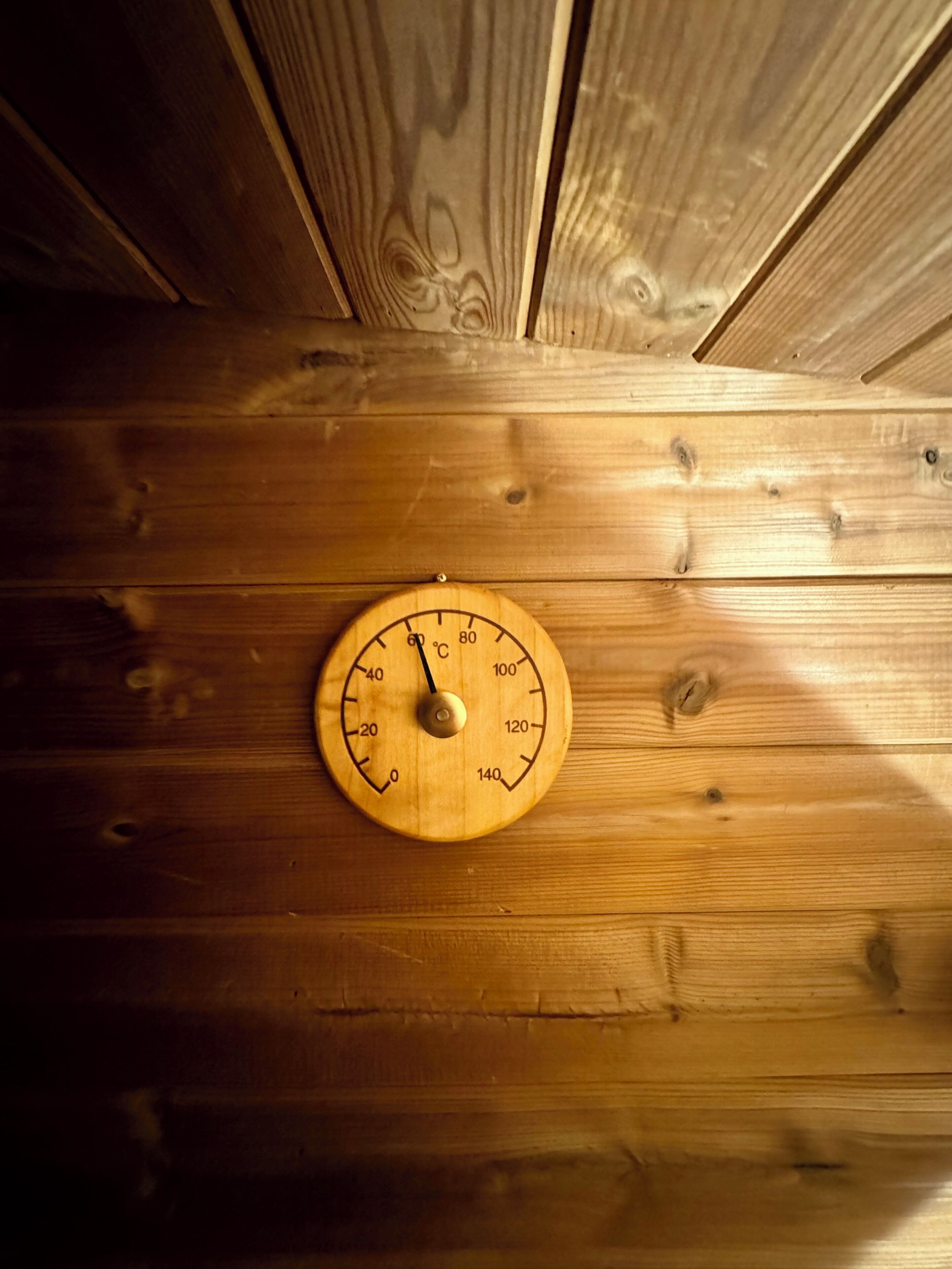 Una pared de madera con un termostato redondo de madera.