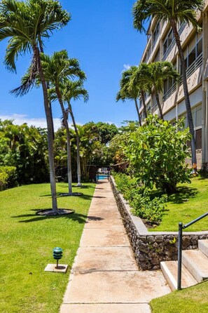 Stroll through lush gardens to a modern building with a swimming pool.