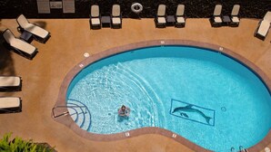 An oval-shaped swimming pool with lounge chairs and a diving board. - 180° Ocean views • Luxe condo • Steps to Beach (Kihei)