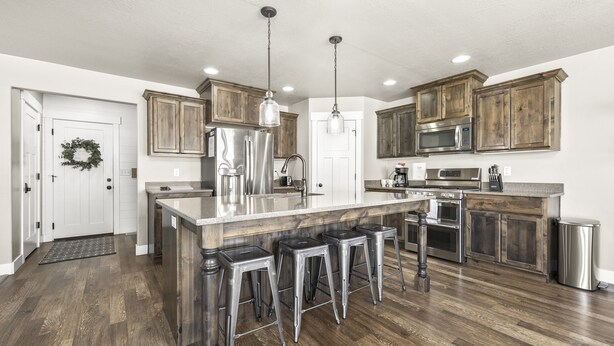 A modern kitchen with wooden cabinets, stainless steel appliances, and a central island with bar stools.