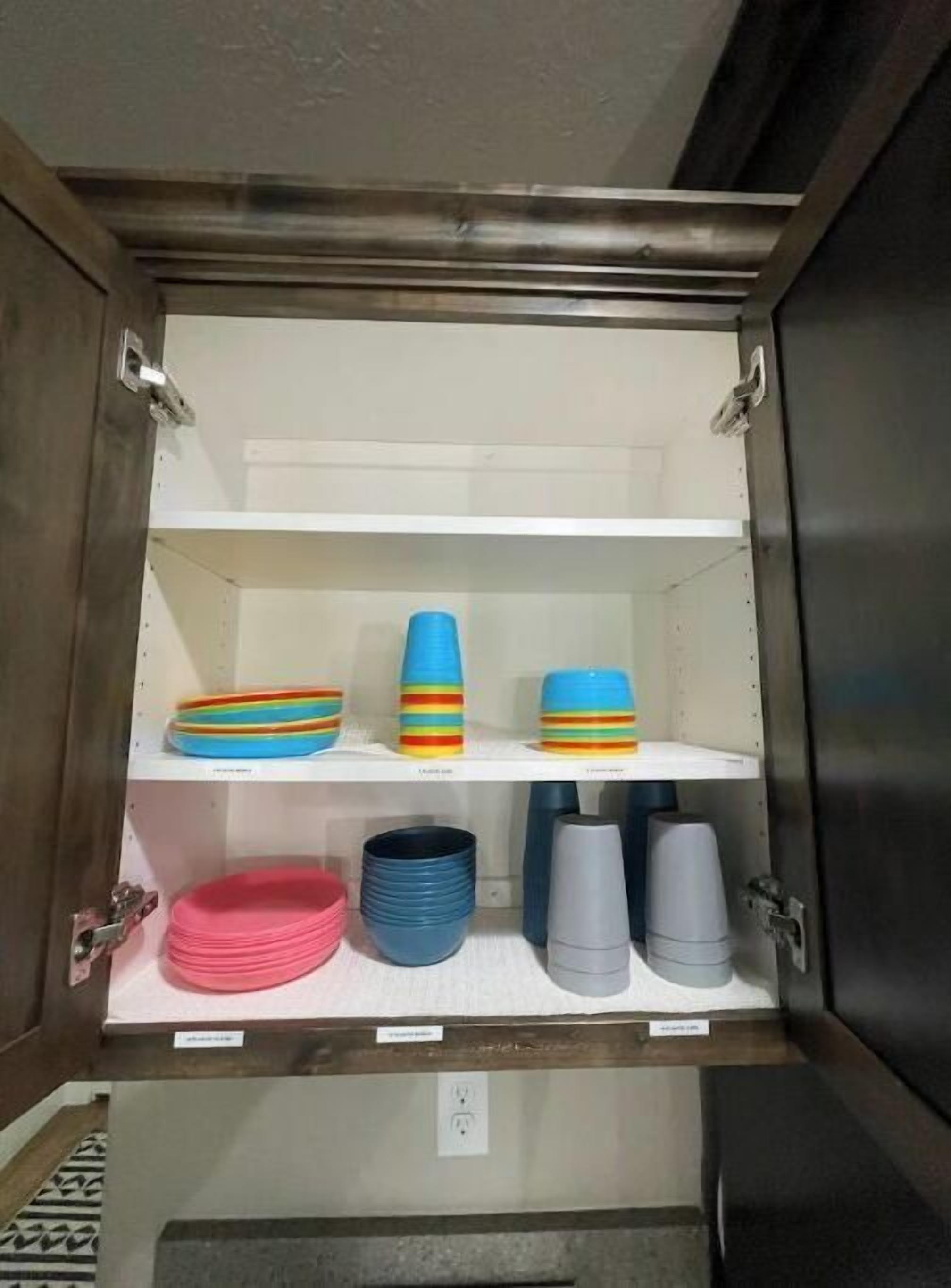 A cabinet with shelves containing colorful plates and cups.