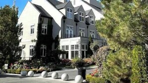 A large, multi-story building with a symmetrical facade, large windows, and a prominent chimney.