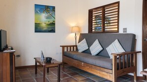 Ein Wohnzimmer mit einer Couch, einem Tisch, einer Lampe und einem Bild mit Strandmotiv.