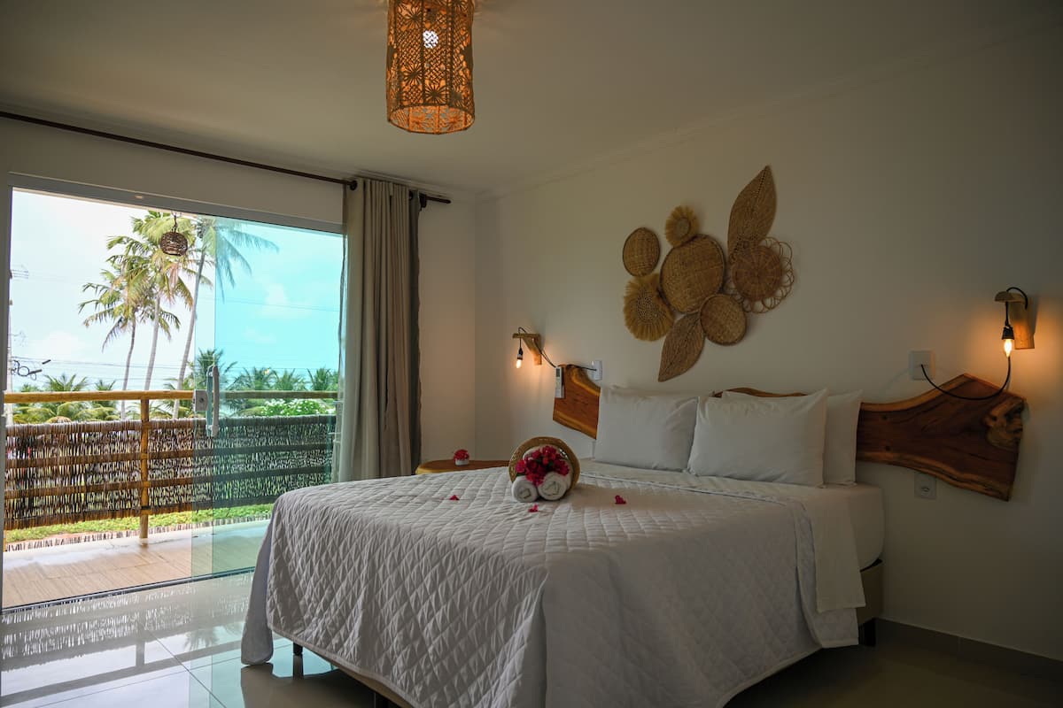 A bedroom with a large bed, a view of palm trees, and a balcony.