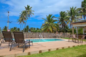 Una piscina al aire libre, sombrillas, sillones reclinables de piscina