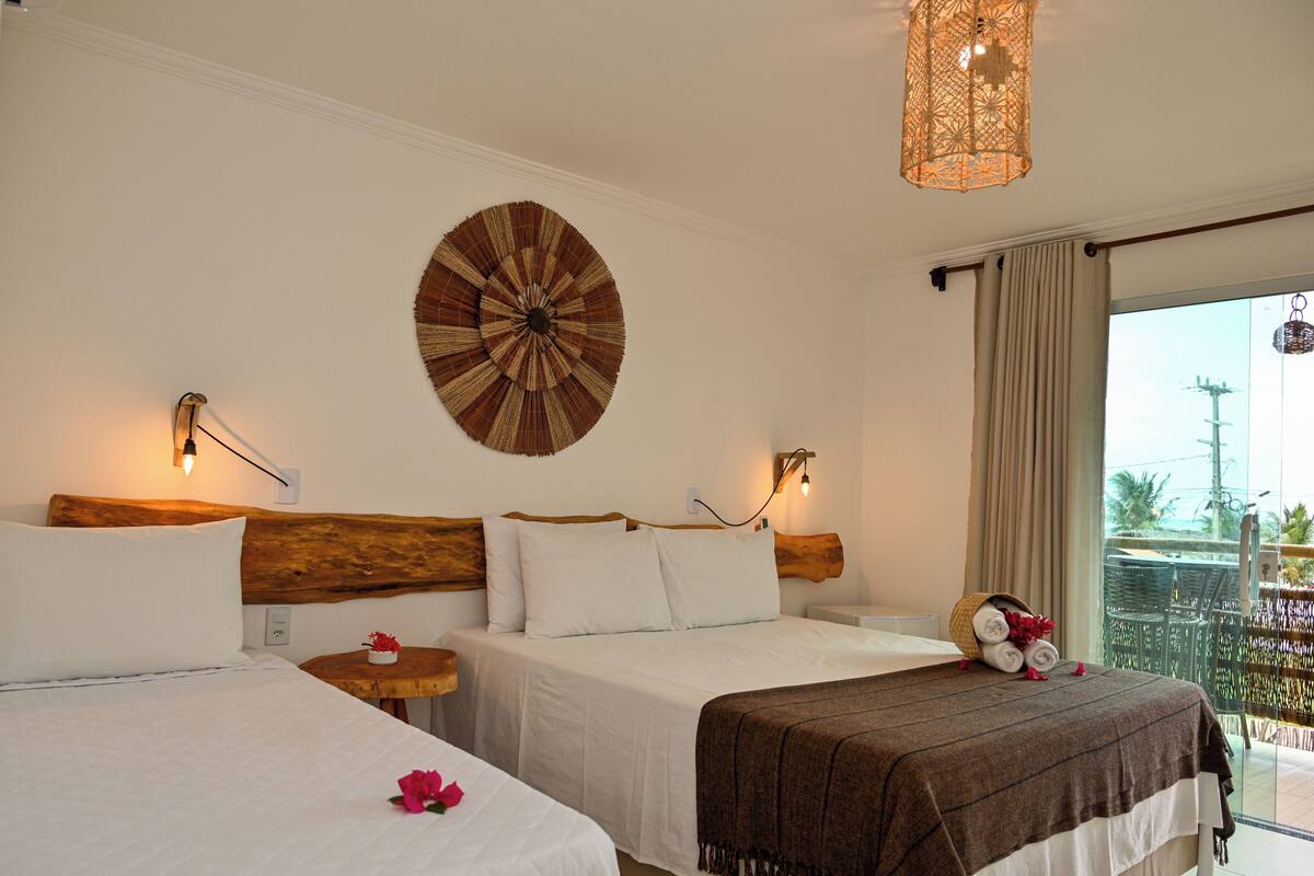 A hotel room with two beds, a large circular wall decoration, and a balcony with a view.