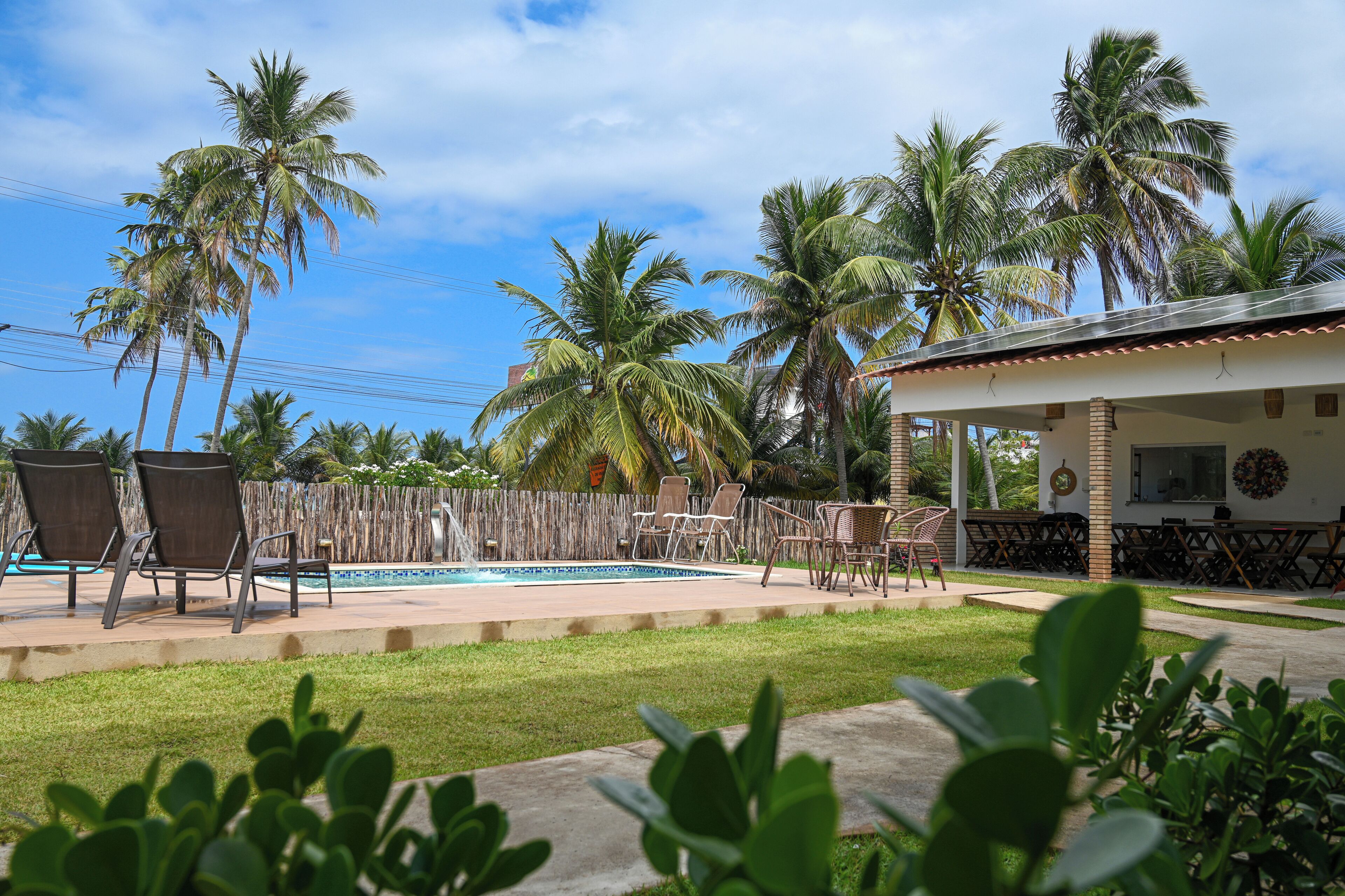 A backyard with a swimming pool, palm trees, and outdoor furniture.