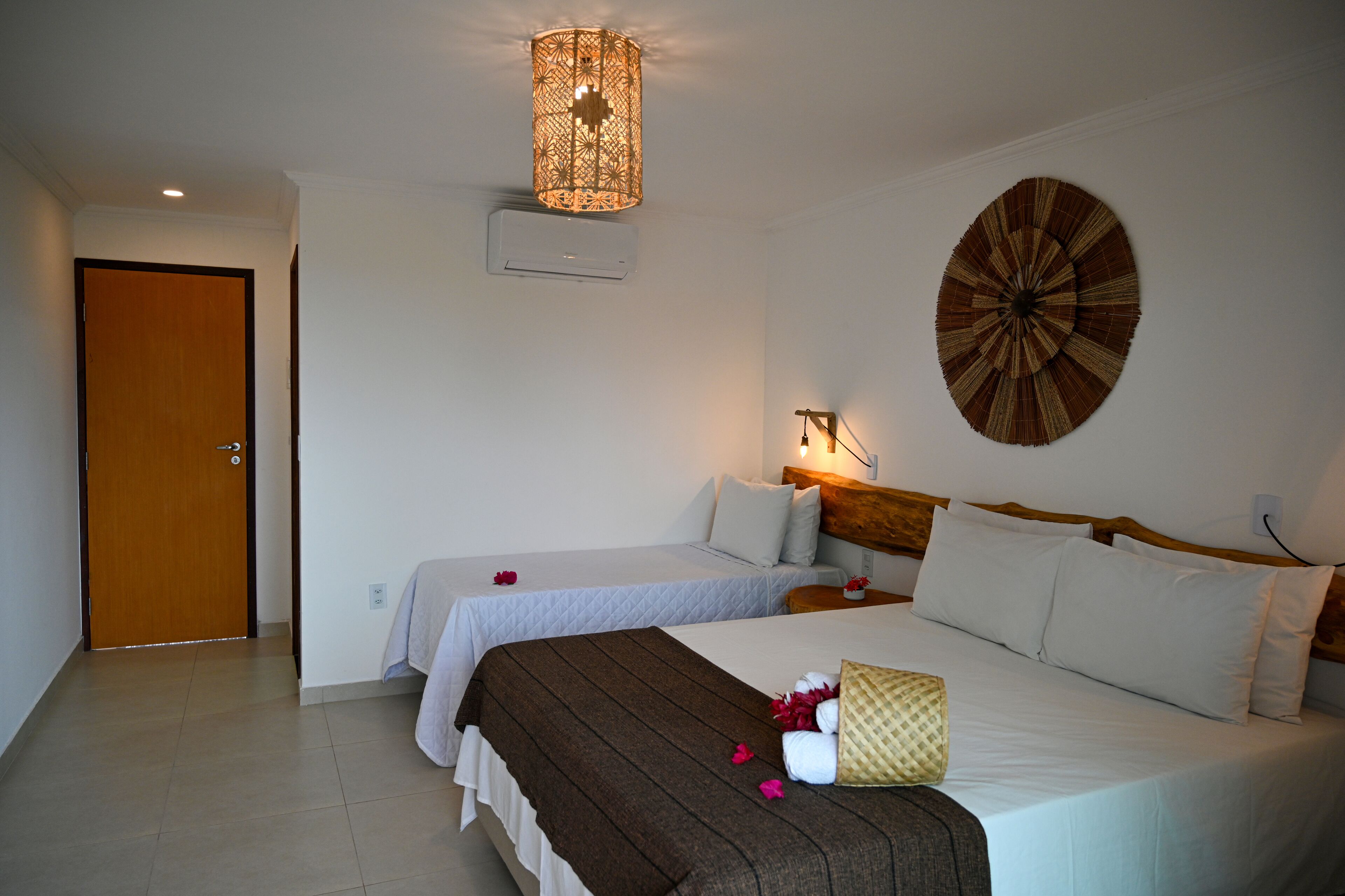 Habitación de hotel con dos camas, cabecero de madera, lámpara de pared y un adorno mural.
