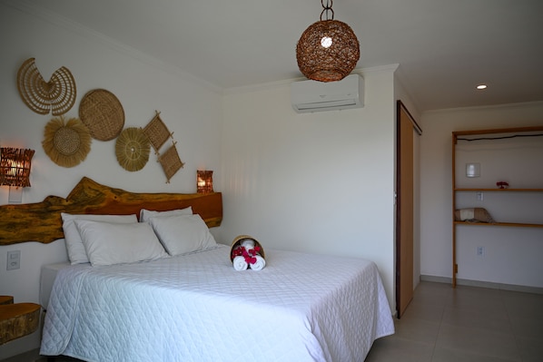 A neatly arranged bedroom with a large bed, a wooden headboard, and decorative wall hangings.