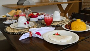 A breakfast table set with plates, bowls, and a coffee pot. - Pousada Estação do Mar (Japaratinga)