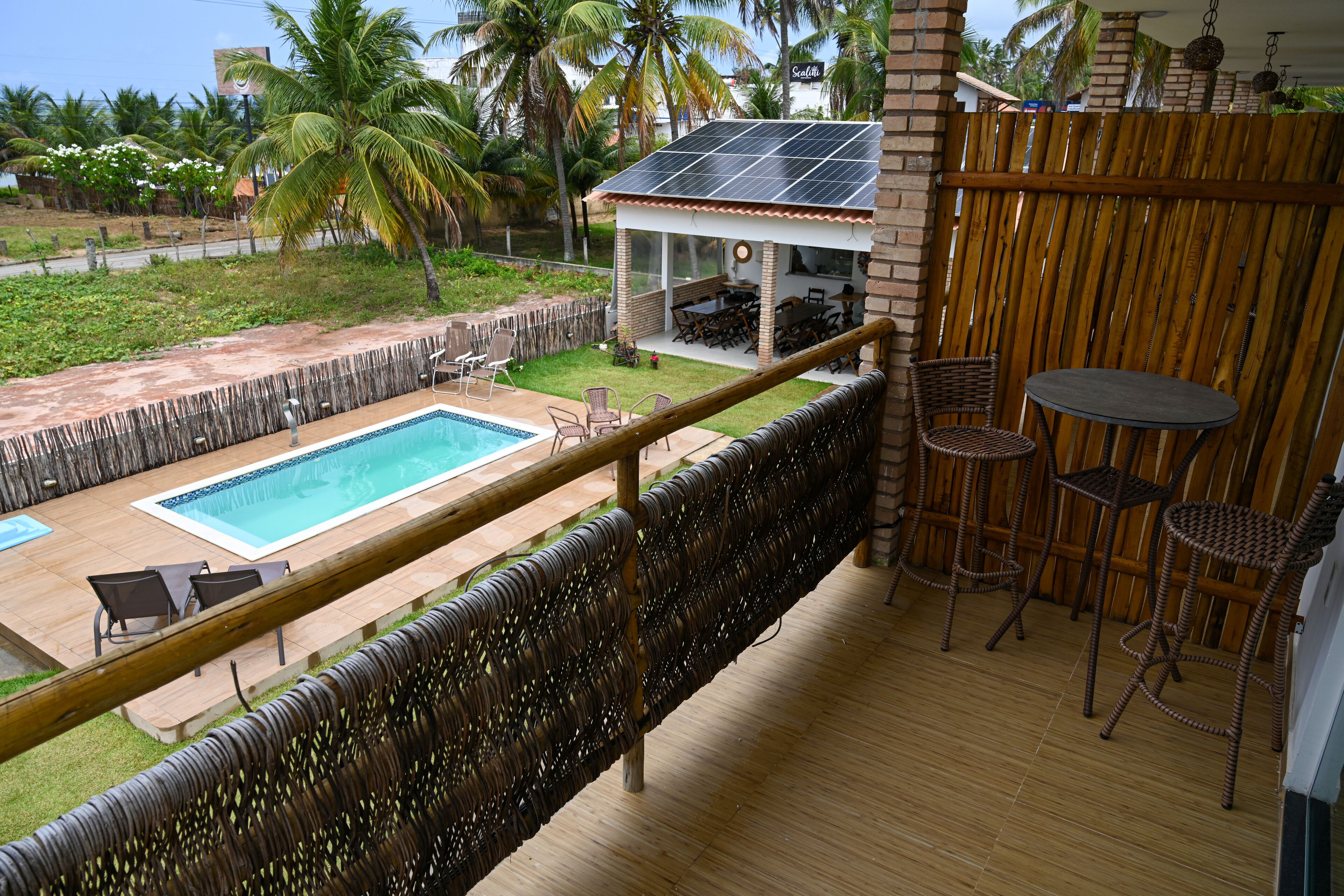 A balcony with a pool, outdoor seating, and a view of the surrounding area.