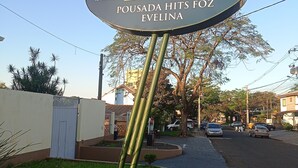 A sign for Pousada Hits Foza with contact numbers. - Pousada Hits Foz (Foz do Iguaçu)