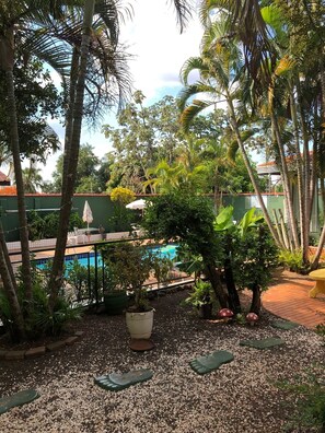 A pool area surrounded by tropical plants and a fenced pool. - Pousada Hits Foz (Foz do Iguaçu)