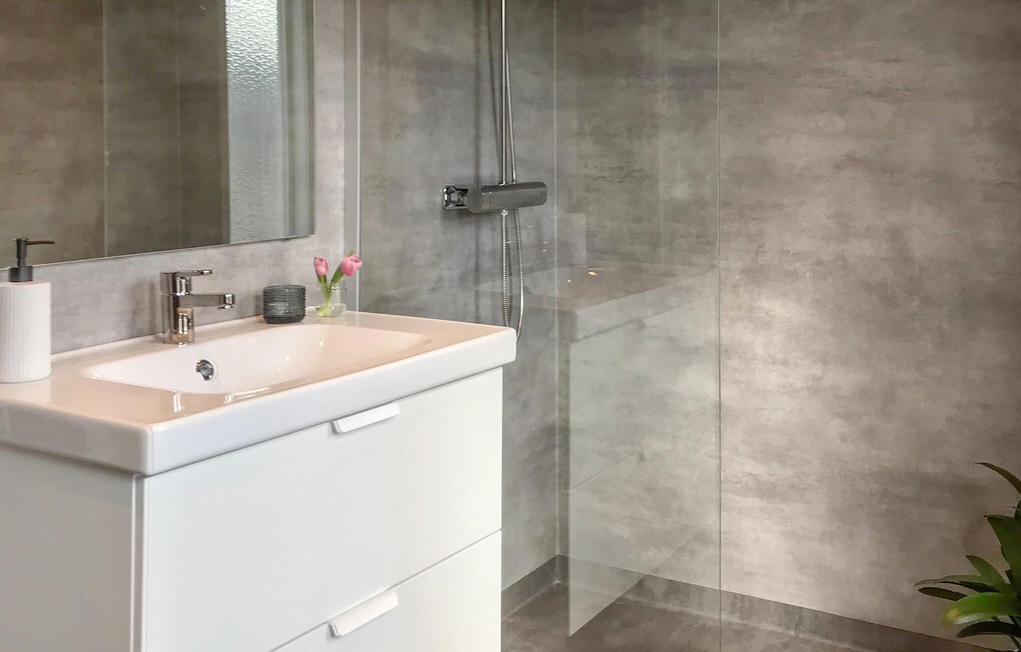 Une salle de bain moderne avec un meuble-lavabo blanc, une cabine de douche en verre et un grand miroir.