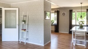 A spacious living area with a wooden floor, a white door, a white ladder, and a white table with shelves. - Awesome home in Kvillsfors with WiFi (Kvillsfors)