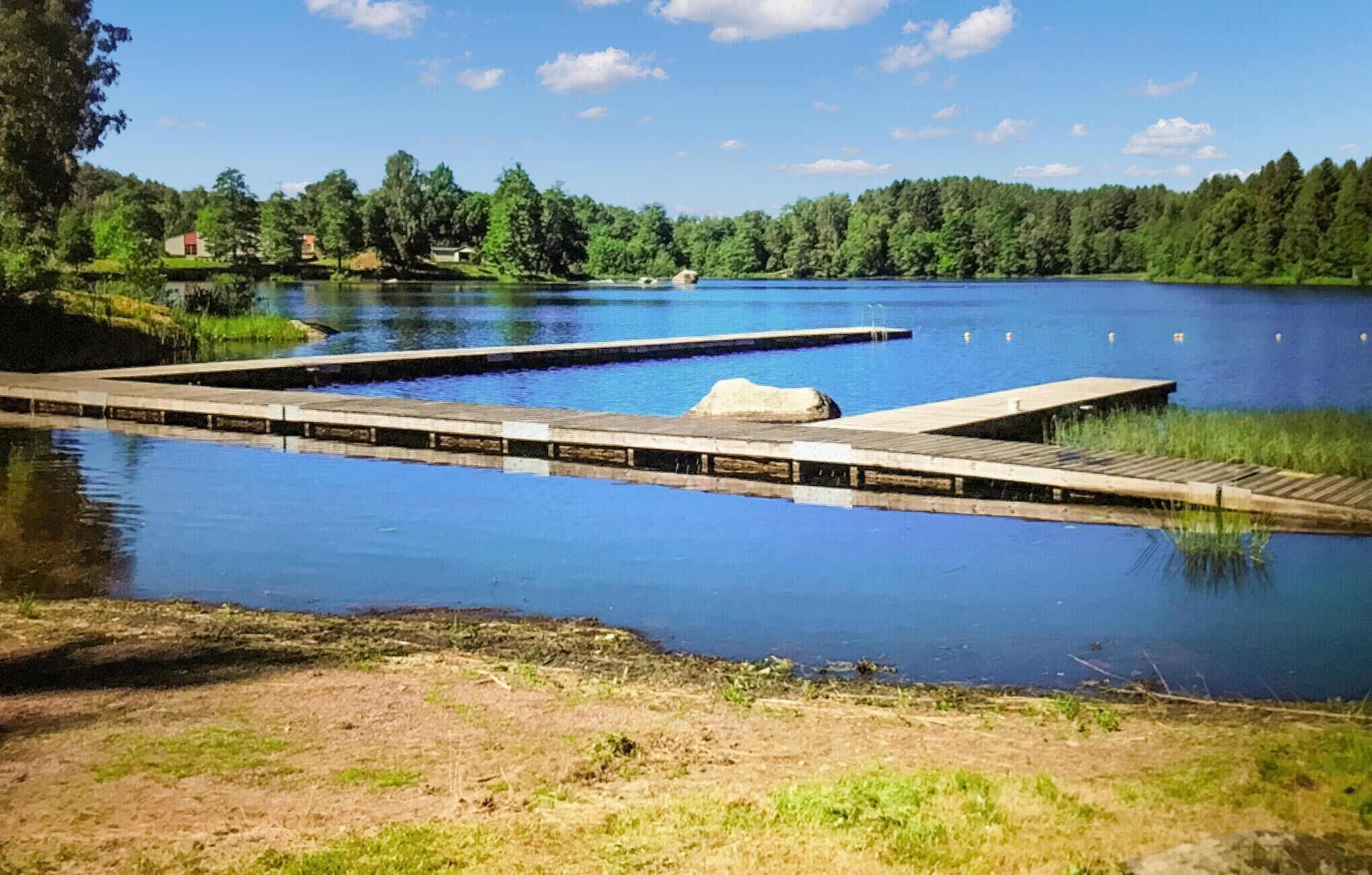 A calm lake with wooden docks extending into the water, surrounded by dense forest.