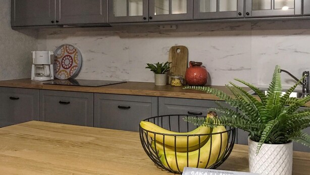 A kitchen with grey cabinets, a wooden countertop, a coffee maker, a decorative plate, a potted plant, a cutting board, a red pot, and a banana bowl. - Awesome home in Kvillsfors with WiFi (Kvillsfors)