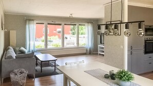 A modern kitchen with a dining area, large windows, and a view of a red brick building. - Awesome home in Kvillsfors with WiFi (Kvillsfors)
