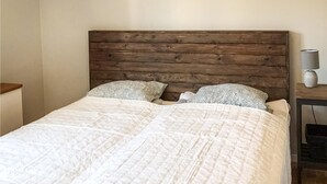 A bed with a wooden headboard, two patterned pillows, and a white quilt. - Awesome home in Kvillsfors with WiFi (Kvillsfors)