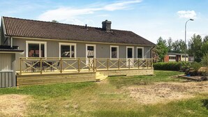 A single-story house with a tiled roof, a wooden deck, and a fenced patio area. - Awesome home in Kvillsfors with WiFi (Kvillsfors)