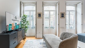 A modern living room with a sofa, a TV on a cabinet, and a plant. - GuestReady - Amazing Studio in the heart of Porto (Porto)