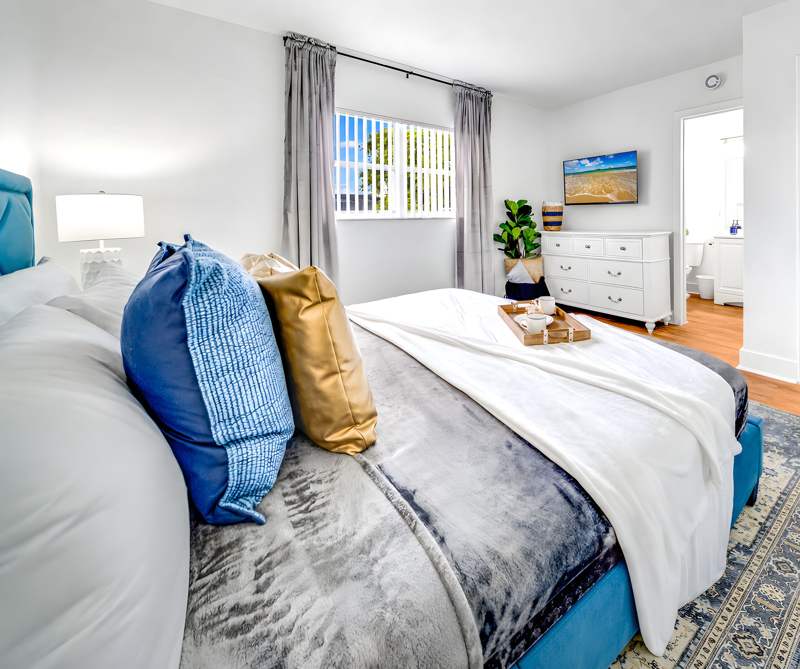 Une chambre à coucher bien rangée, avec un lit, une table de chevet et une fenêtre avec des rideaux.