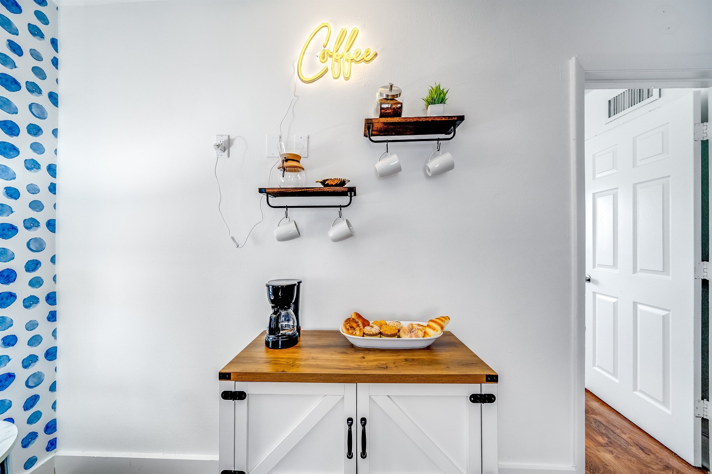 Une cuisine équipée d’un coin café, d’un néon et d’un saladier rempli de viennoiseries.