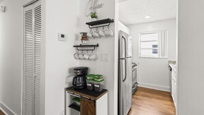 Eine moderne Küche mit Einbaukühlschrank, einer Kaffeestation und einem Fenster mit Jalousien.