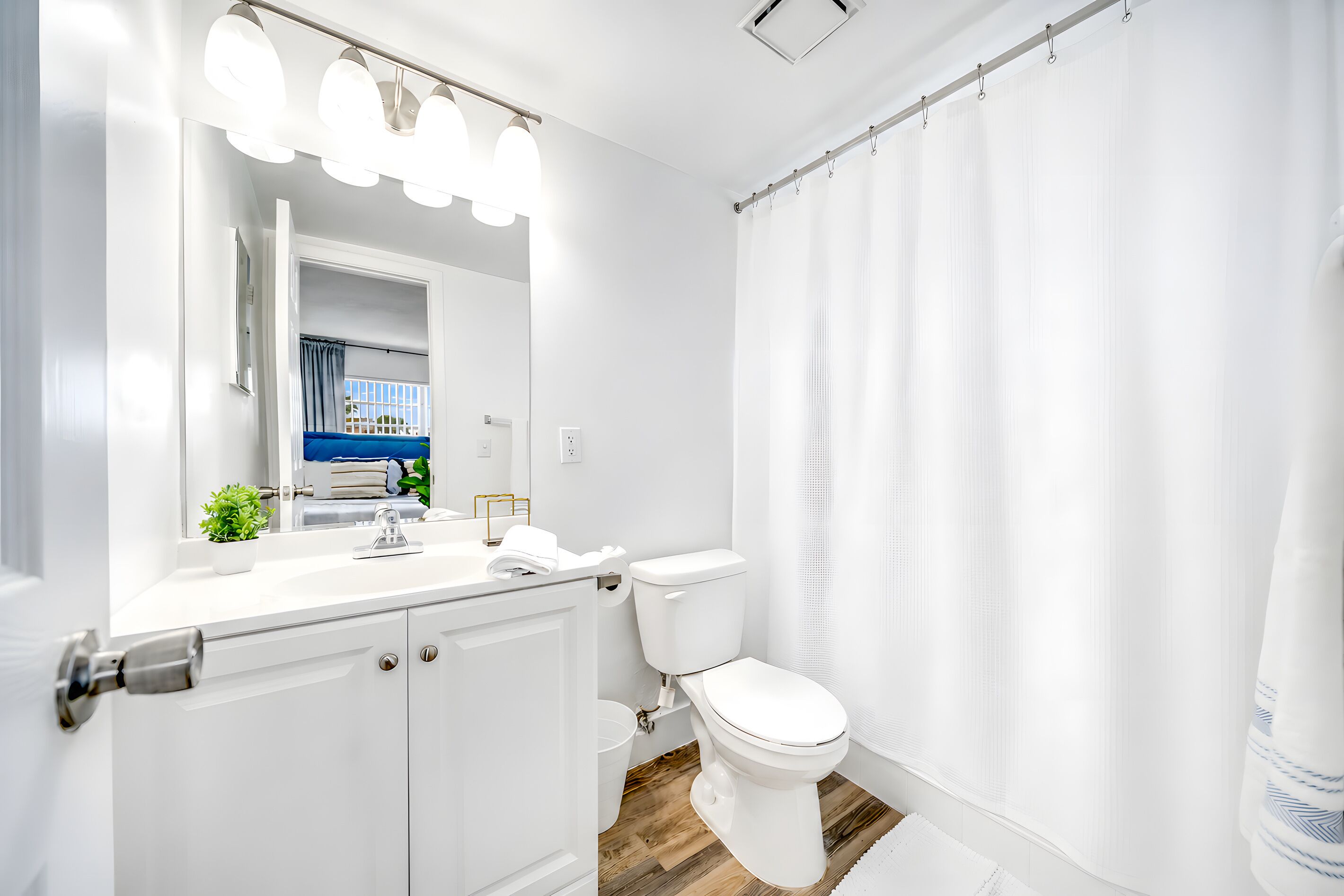 Un baño moderno con inodoro blanco, lavamanos con espejo y cortina de ducha.