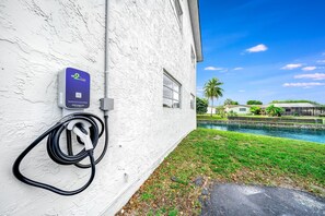 An electric vehicle charging station mounted on a white wall next to a pool.