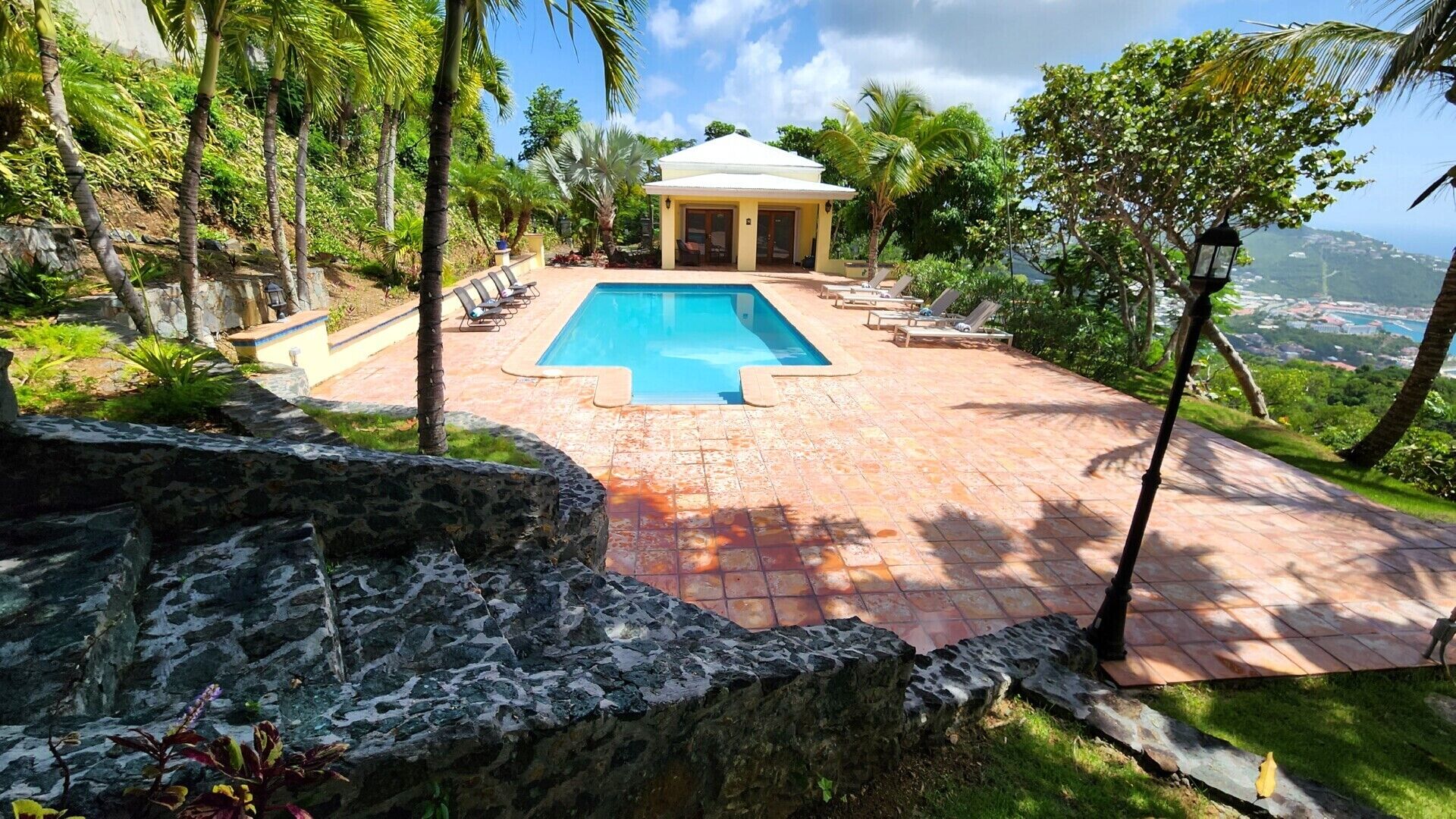 A pool area with lounge chairs, a gazebo, and a view of the landscape.