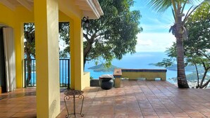 Une terrasse couverte avec vue sur la mer, un sol carrelé et une petite table.