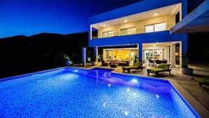 A modern two-story house with a swimming pool at dusk.