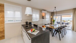 A modern kitchen with a central island, bar stools, and a dining area with a view.