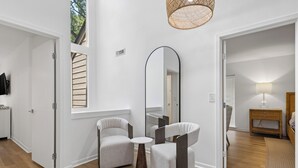 Ein modernes Interieur mit zwei Sesseln, einem runden Tisch, einem großen Spiegel und einer Weidenleuchte.