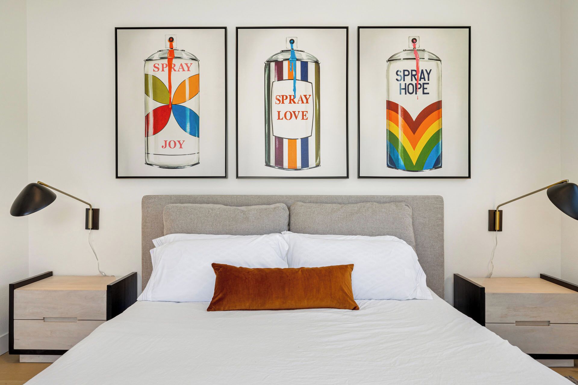 Un dormitorio con una cama, dos mesitas de noche y tres obras de arte enmarcadas en la pared.