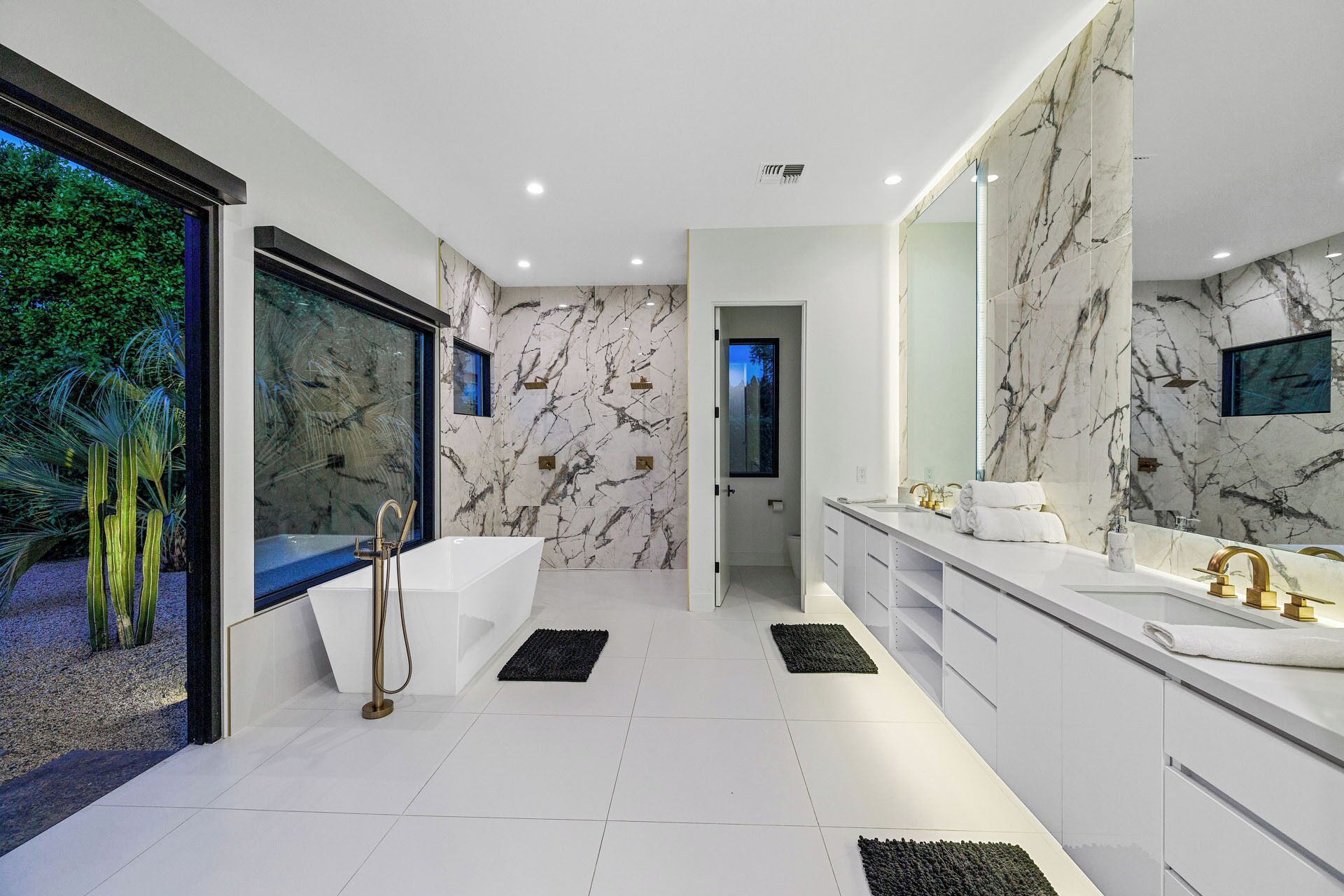 Une salle de bain moderne dotée d’une grande baignoire, de deux lavabos et d’une douche à l’italienne.