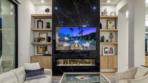 Un soggiorno moderno con una grande TV a schermo piatto, comodi posti a sedere e un caminetto.