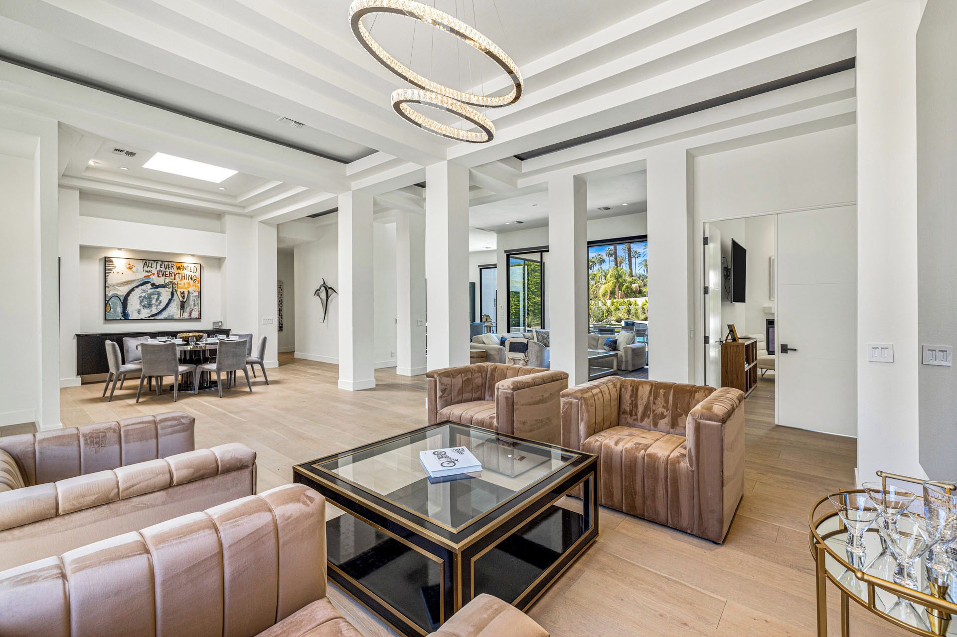 A spacious living area with leather sofas, a glass coffee table, and a modern chandelier.