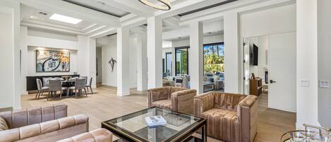 A spacious living area with leather sofas, a glass coffee table, and a modern chandelier.