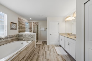 A modern bathroom with a large bathtub, a glass shower enclosure, and a vanity with a sink and mirror.