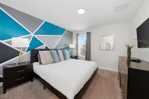 A bedroom with a bed, nightstands, a dresser, a mirror, and a geometric wall design. - Games Room | Kids Bedrooms | Screened Pool Area (Davenport)