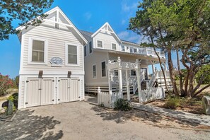 A two-story white house with a covered porch and a fenced driveway.