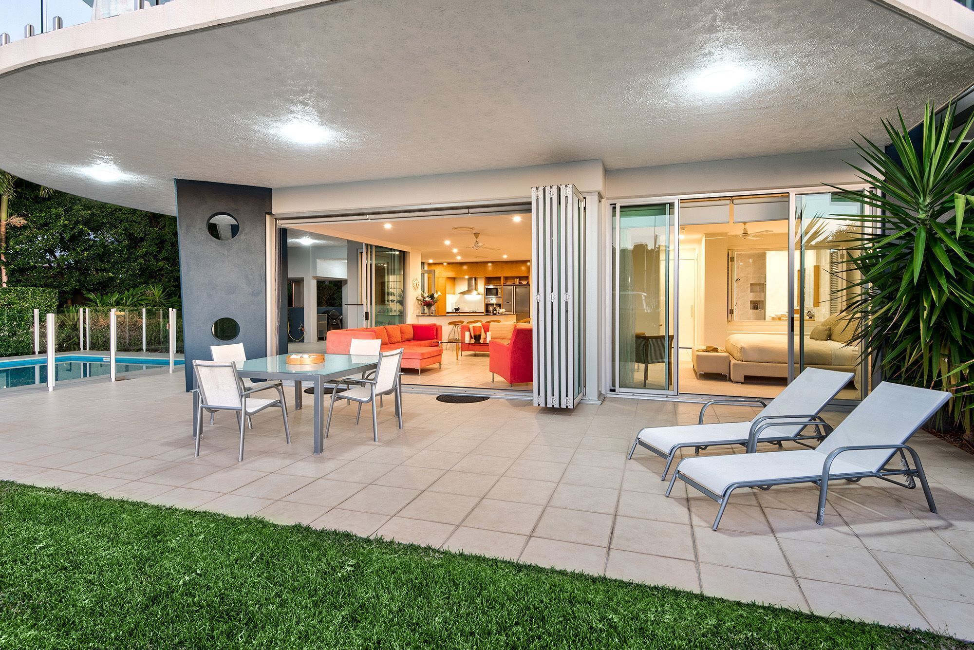 An outdoor patio with a pool, a dining area, and lounge chairs.