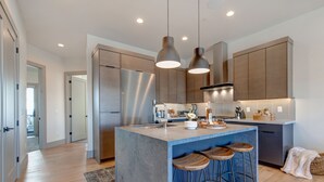 A modern kitchen with a central island, stainless steel appliances, and pendant lighting. - Walk to Gondola: Perfect for Adventures with Private Hot Tub, BBQ & Views! (Park City)