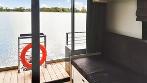 A boat cabin with a wooden deck, a cushioned bench, a metal railing, and a lifebuoy. - Cozy ship in Havelsee OT Kützkow (Havelsee OT Kützkow)