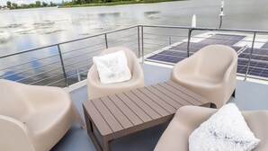 A deck with two chairs and a table, solar panels, and a railing overlooking a body of water. - Cozy ship in Havelsee OT Kützkow (Havelsee OT Kützkow)