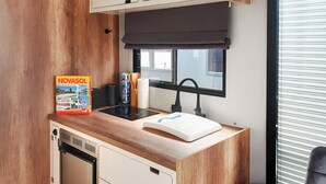 A compact kitchenette with a stove, sink, and a window with blinds. - Cozy ship in Havelsee OT Kützkow (Havelsee OT Kützkow)